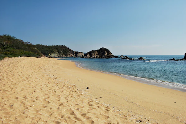 Conejos Bay beach near Secrets Huatulco Resort & Spa with golden sand, rocky coves, and calm Pacific waters