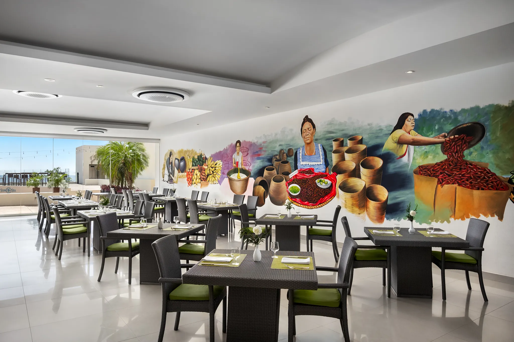 Market Café buffet at Secrets Huatulco Resort & Spa featuring bright modern dining space, international food stations, and colorful mural décor.