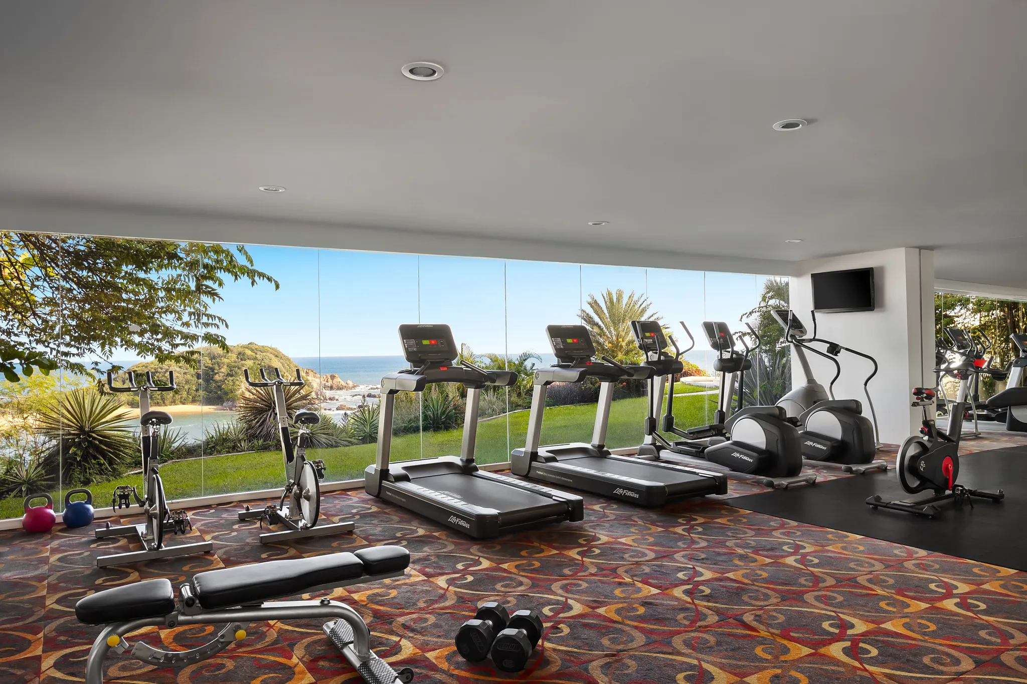 Ocean-view fitness center with treadmills and exercise equipment at Secrets Huatulco Resort & Spa.