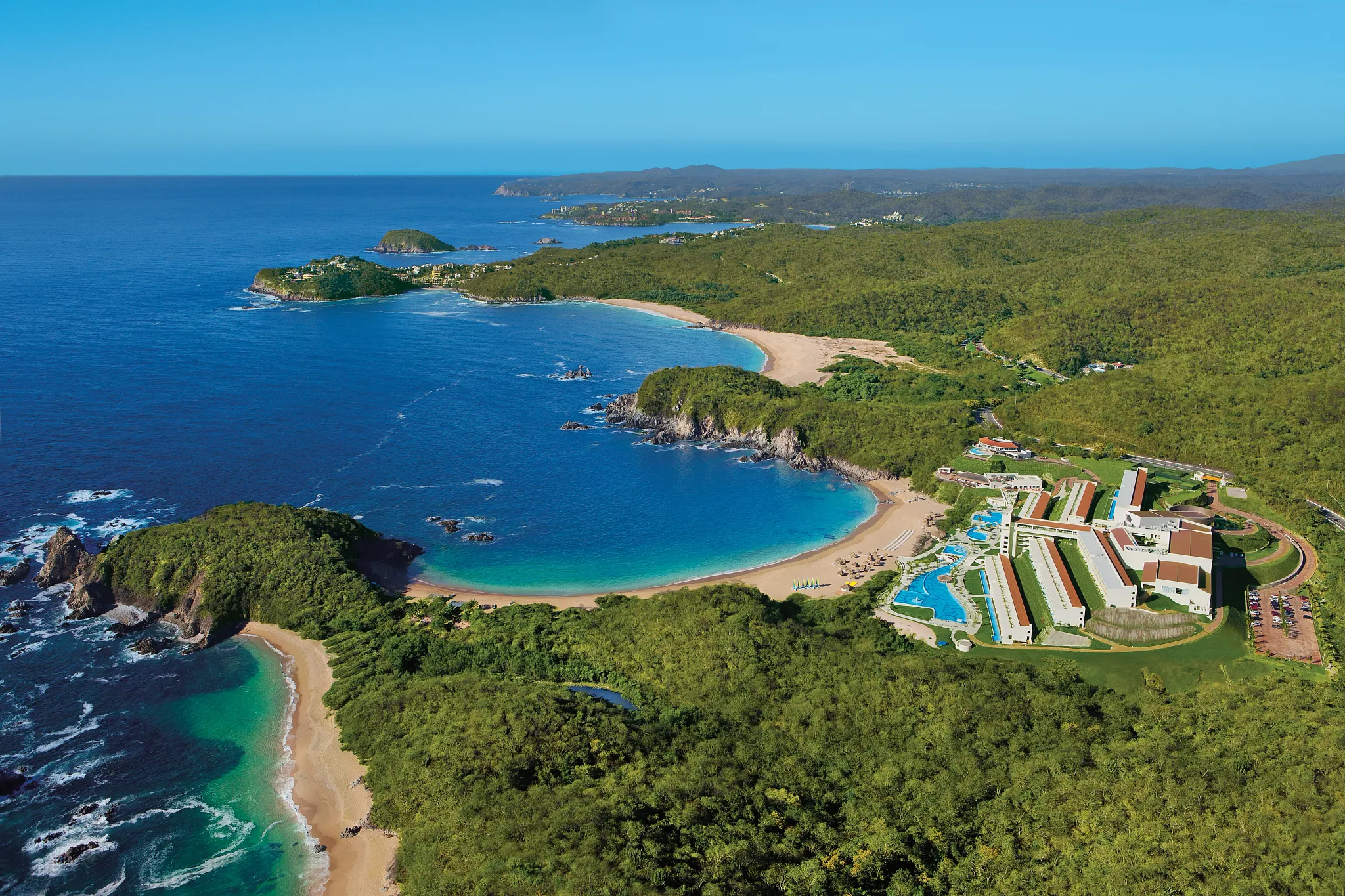 Panoramic aerial view of multiple bays and Secrets Huatulco Resort & Spa along Oaxaca’s Pacific coastline.
