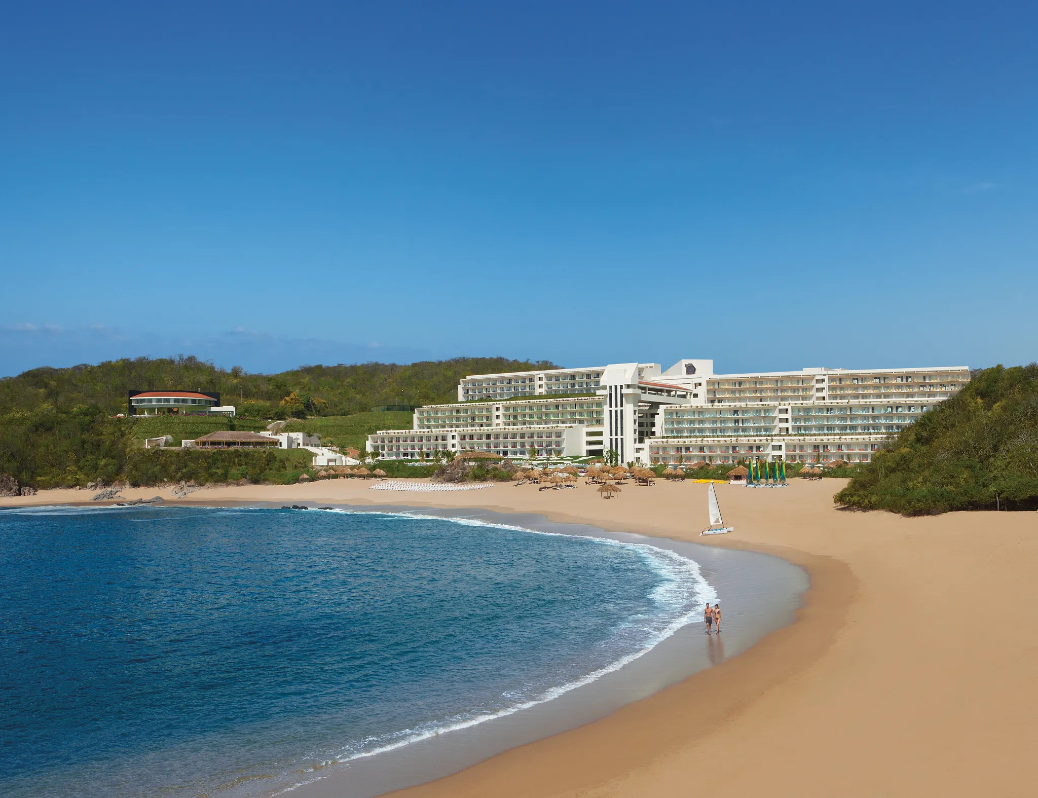 Panoramic view of Secrets Huatulco Resort & Spa along a crescent-shaped beach with calm waters and golden sand.