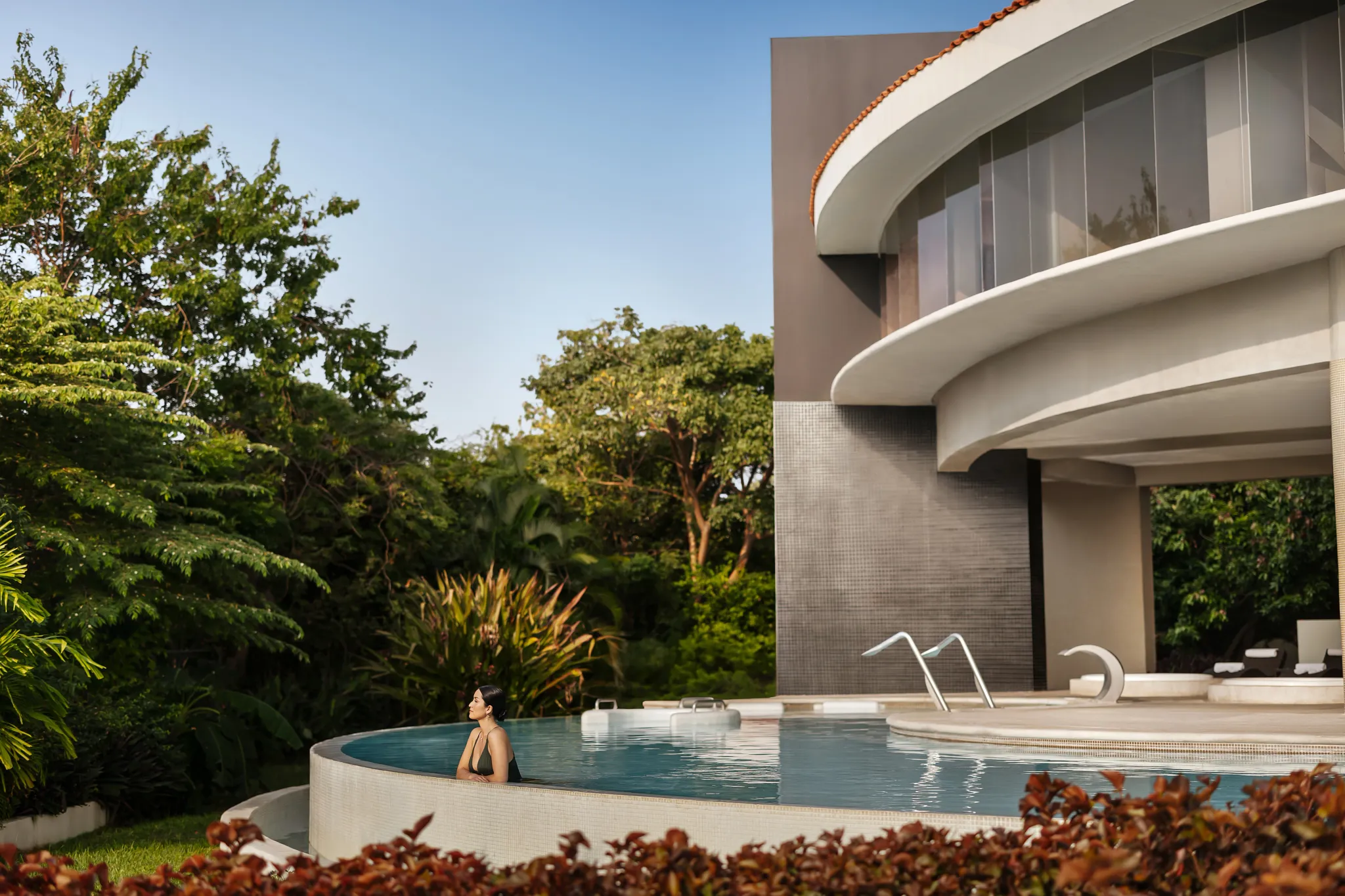 Spa exterior and pool area at Secrets Huatulco Resort & Spa surrounded by tropical greenery and modern architecture.