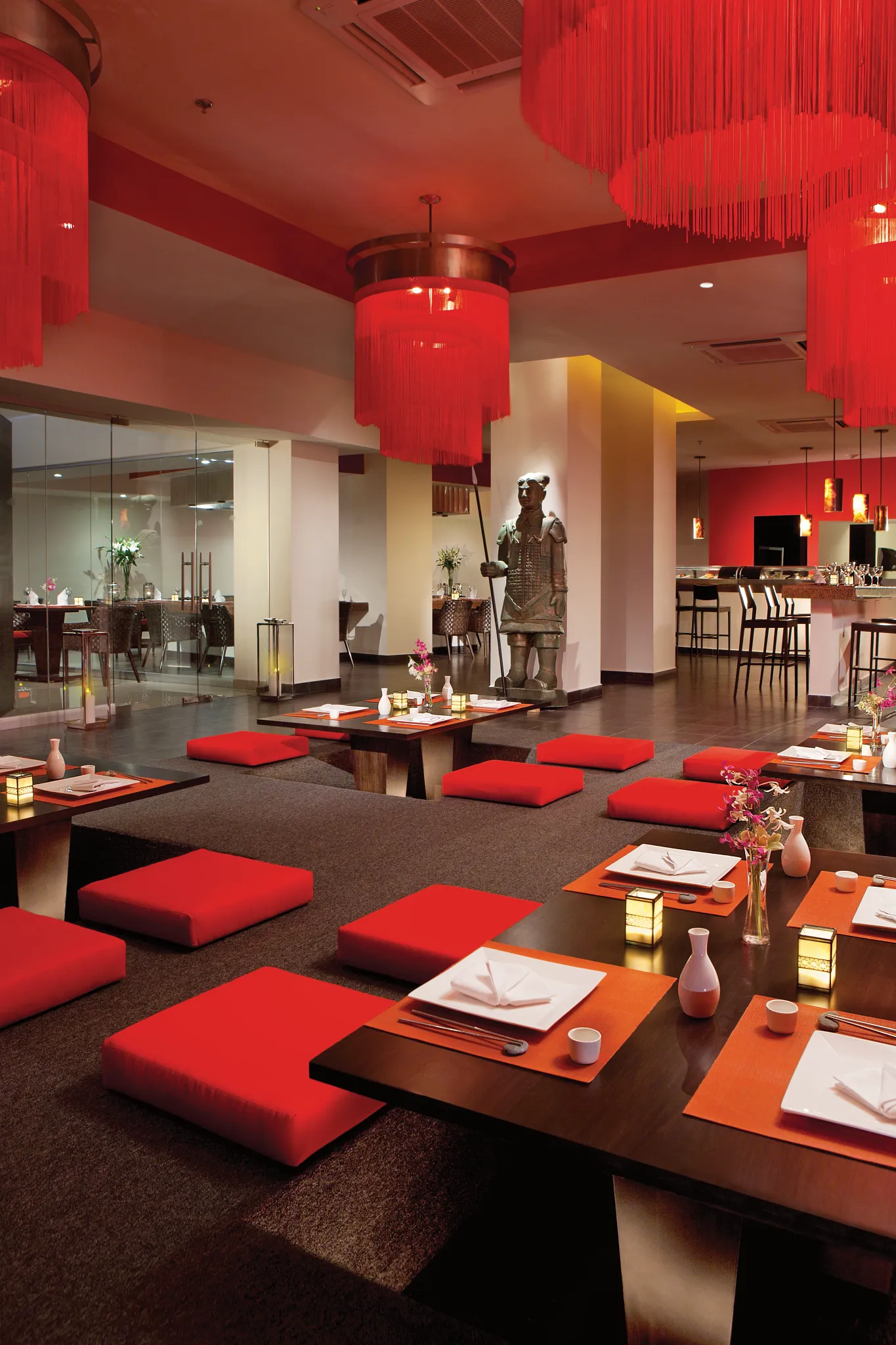 Spice Pan-Asian restaurant at Secrets Huatulco Resort & Spa featuring low seating, red décor accents, and an elegant Asian-inspired dining atmosphere.